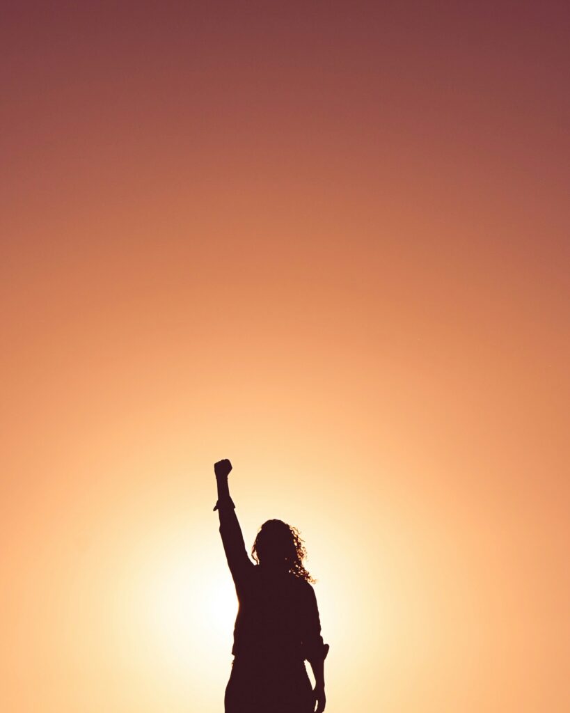 Silhouette of a person with long hair with their fist raised